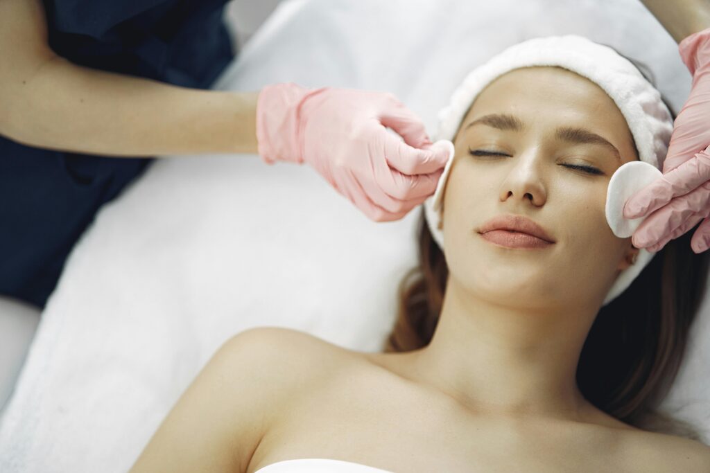 Profesional realizando una limpieza facial en cabina a una clienta durante un tratamiento facial.